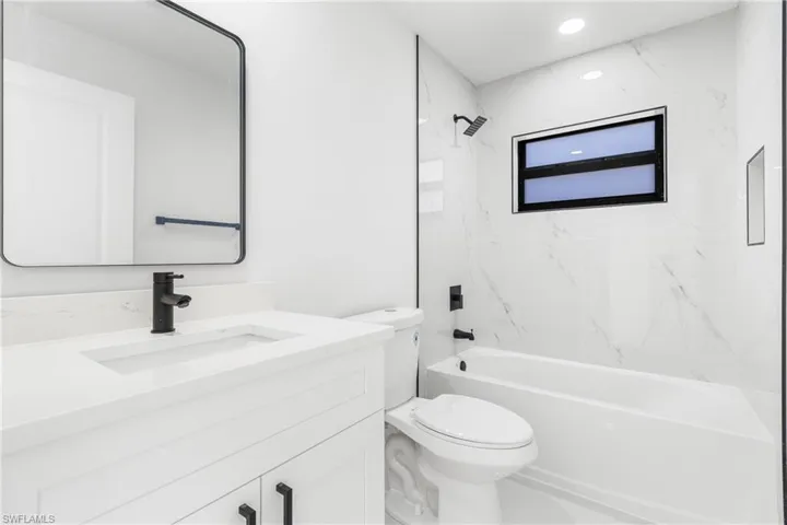 Bathroom with vanity, shower / bath combination, and recessed lighting