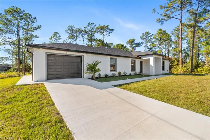 View of front of property featuring a front lawn, driveway, stucco siding, and a garage