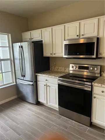 Kitchen with white cabinets, range, and fridge