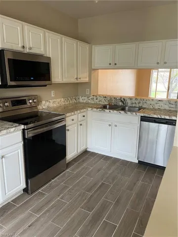 Kitchen featuring dishwasher, white cabinetry, range, and sink