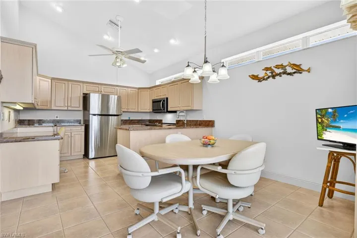 Dining space featuring high vaulted ceiling, light tile patterned floors, a ceiling fan, a chandelier, and recessed lighting