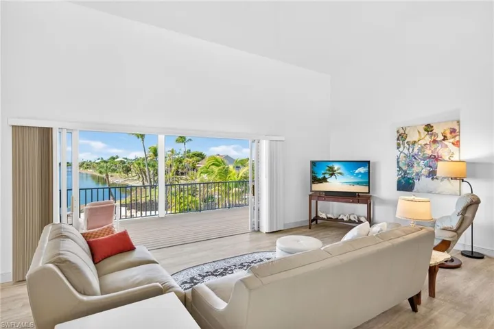 Living room with high vaulted ceiling, light wood-style floors, and a water view
