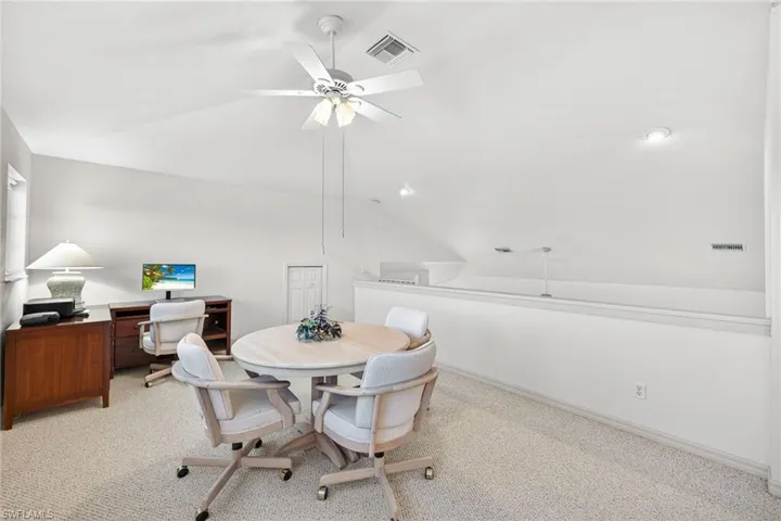 Carpeted loft with vaulted ceiling and ceiling fan