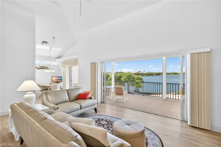 Living area featuring healthy amount of natural light, light wood-style flooring, high vaulted ceiling, and a chandelier