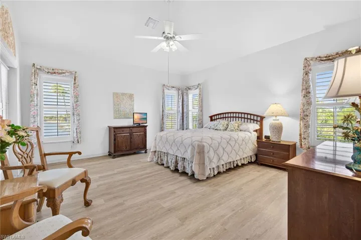 Bedroom with light wood finished floors, multiple windows, and ceiling fan