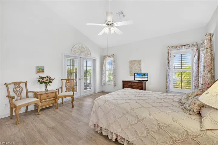 Bedroom featuring french doors, access to outside, high vaulted ceiling, light wood-style floors, and multiple windows