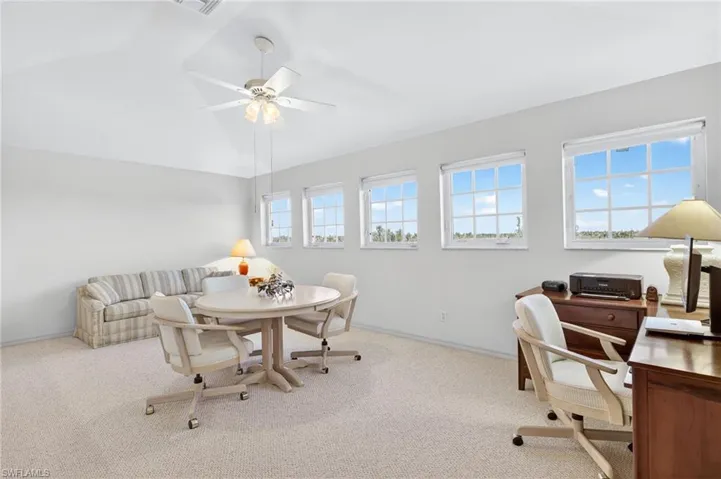 Carpeted loft with a ceiling fan and lofted ceiling