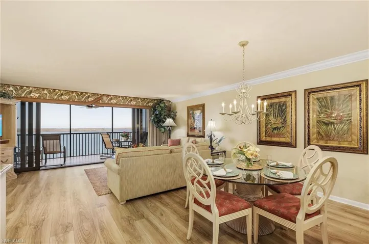 Dining room featuring an inviting chandelier, a water view, ornamental molding, and light wood-type flooring