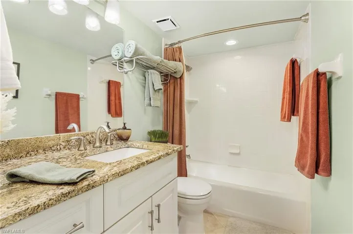 Full bathroom with vanity, shower / bath combination with curtain, toilet, and tile patterned floors