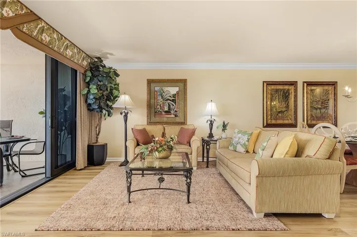 Living room with ornamental molding and light hardwood / wood-style flooring