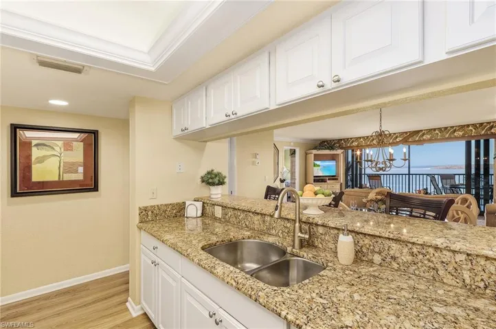 Kitchen featuring sink, white cabinetry, a notable chandelier, and light hardwood / wood-style floors