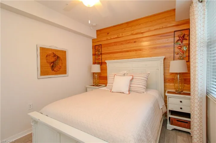 Bedroom with hardwood / wood-style floors, ceiling fan, and wooden walls