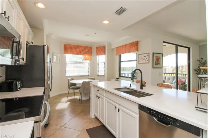 Kitchen featuring a wealth of natural light, sink, decorative light fixtures, white cabinets, and appliances with stainless steel finishes