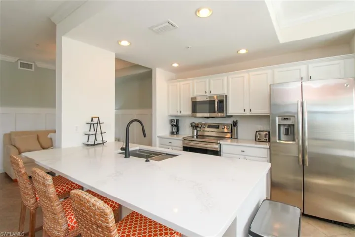 Kitchen featuring a kitchen bar, white cabinetry, sink, and appliances with stainless steel finishes