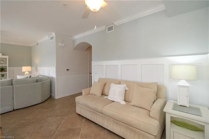 Tiled living room featuring ceiling fan and crown molding
