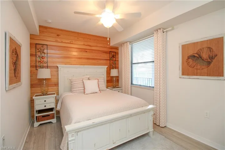 Bedroom with wood walls, ceiling fan, and light hardwood / wood-style floors