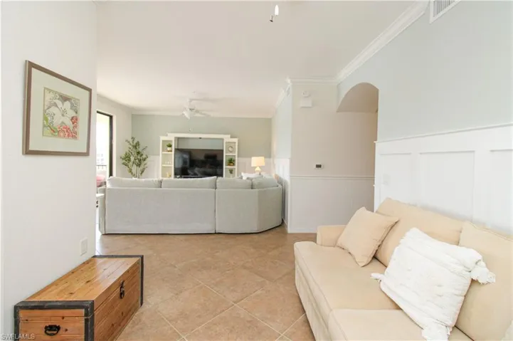 Living room featuring ceiling fan, light tile patterned floors, and crown molding