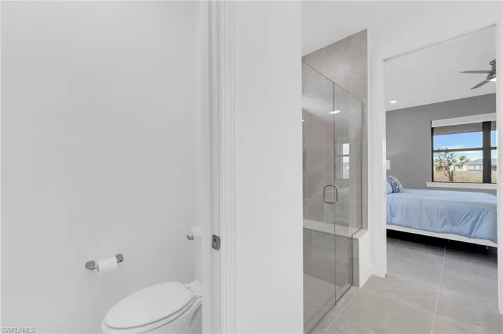 Ensuite bathroom featuring a stall shower and light tile patterned flooring