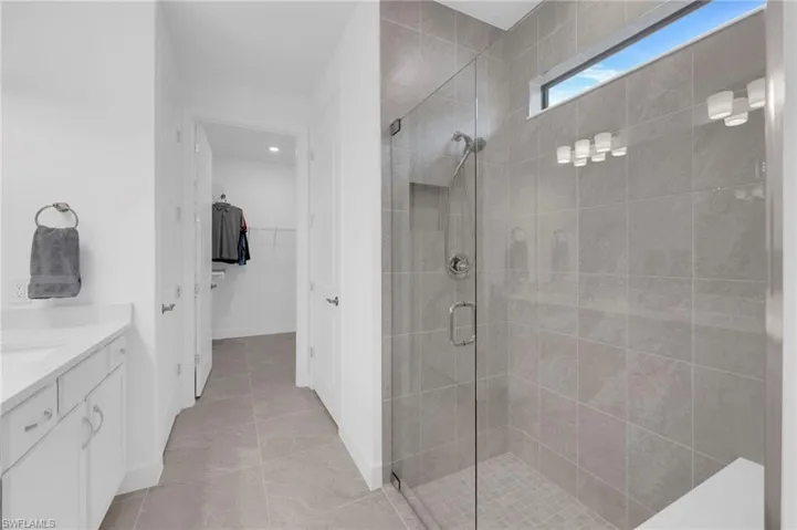 Full bathroom with vanity, a stall shower, and a walk in closet
