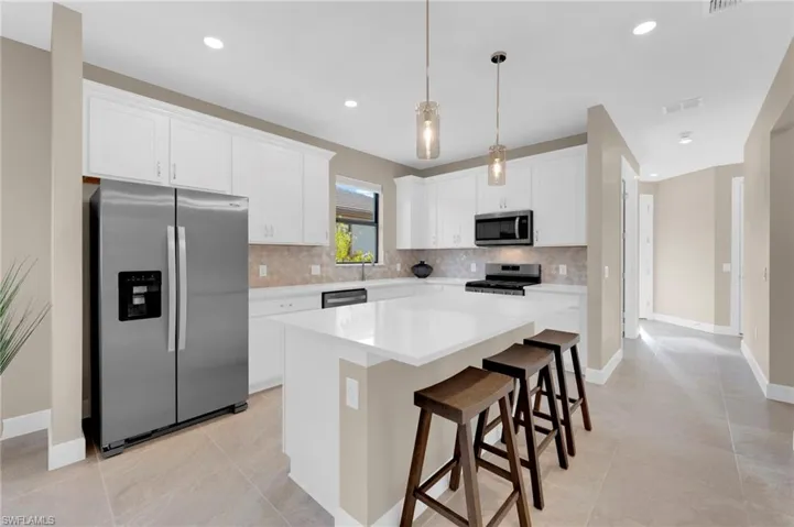 Kitchen with appliances with stainless steel finishes, a kitchen breakfast bar, a center island, white cabinetry, and recessed lighting
