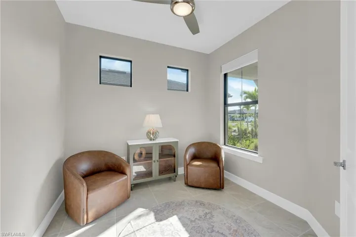 Living area with plenty of natural light, tile patterned floors, and a ceiling fan