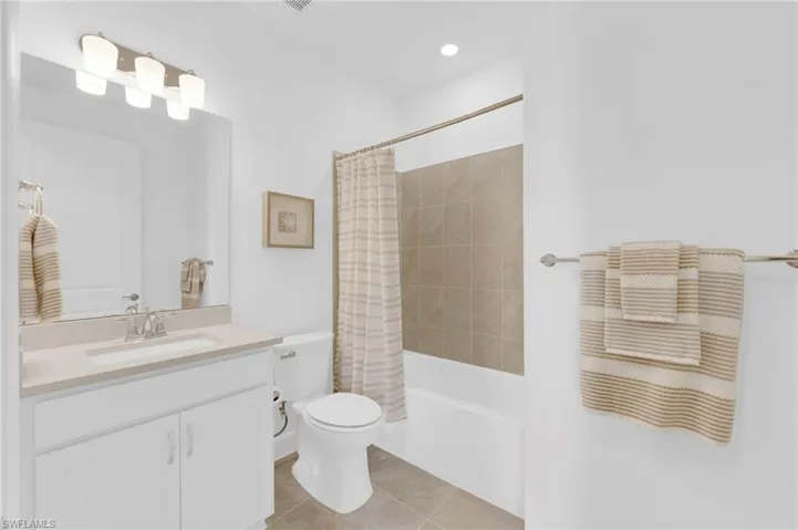 Full bath featuring shower / tub combo with curtain, vanity, light tile patterned floors, and recessed lighting