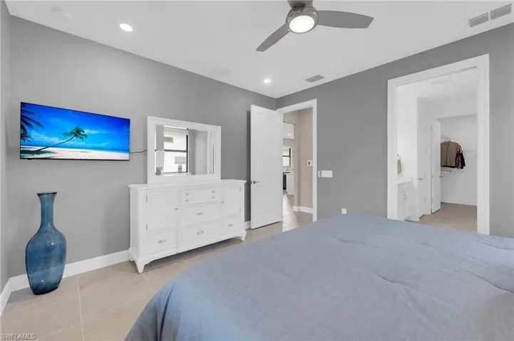 Bedroom with light tile patterned floors, ceiling fan, recessed lighting, and a spacious closet