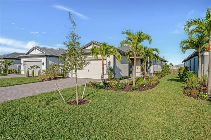 View of front of property with a garage, a front yard, decorative driveway, and stucco siding