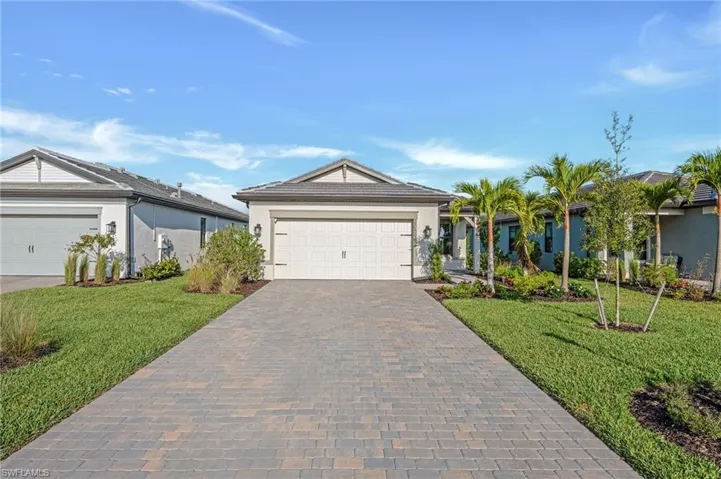 Ranch-style house featuring decorative driveway, a front lawn, stucco siding, and an attached garage