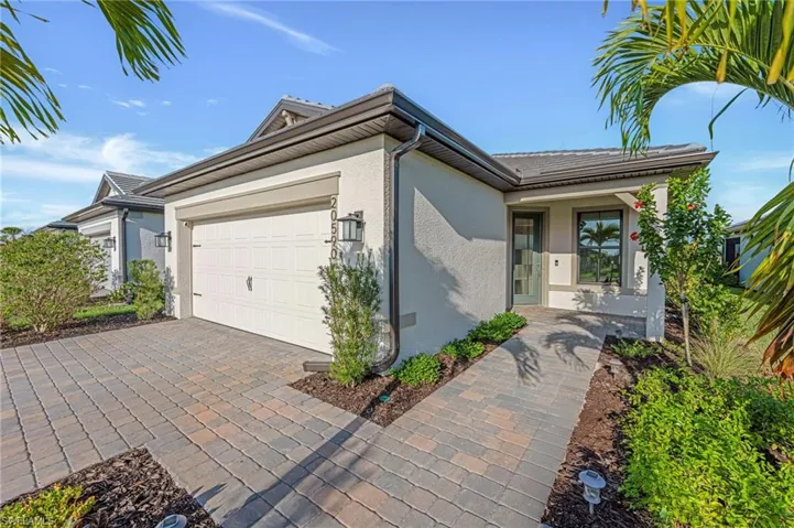 Single story home featuring stucco siding, a garage, and decorative driveway