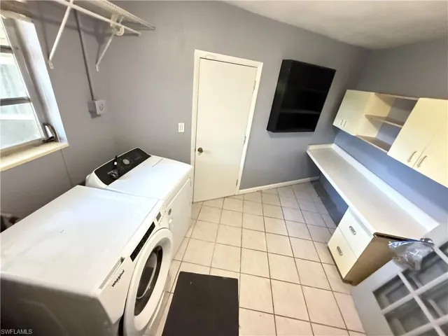 Laundry room with washer and clothes dryer and light tile patterned floors