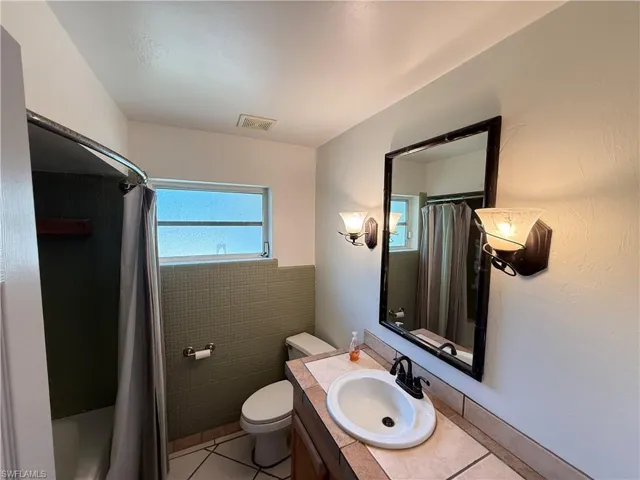 Bathroom featuring vanity, healthy amount of natural light, light tile patterned floors, and shower / tub combo with curtain