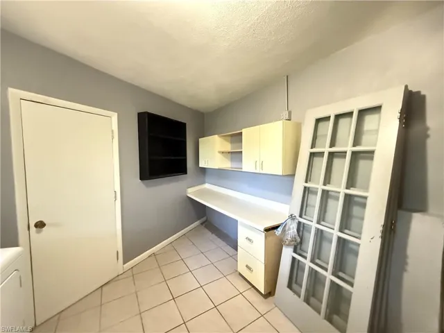 Unfurnished office featuring light tile patterned floors and washer / dryer