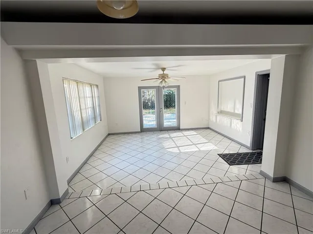 Spare room with light tile patterned floors, a ceiling fan, and french doors