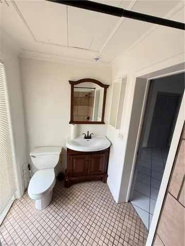 Bathroom featuring vanity, light tile patterned floors, crown molding, and a closet