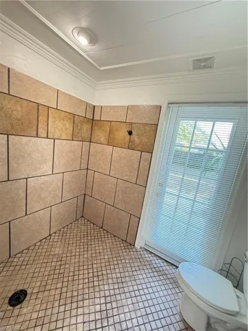 Full bath featuring a shower stall, tile patterned flooring, and crown molding