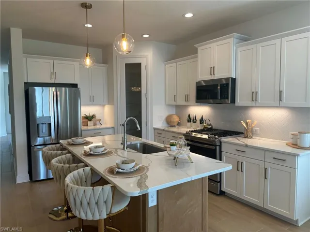 Kitchen featuring backsplash, stainless steel appliances, sink on the center island white cabinets