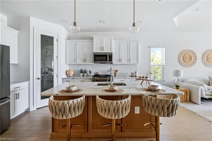 Kitchen featuring decorative light fixtures, a kitchen bar, and stainless steel appliances
