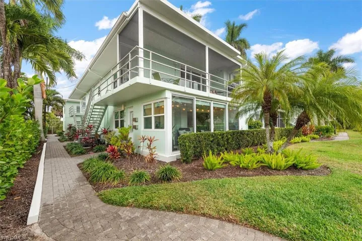 View of side of home with enclosed sunroom and lawn