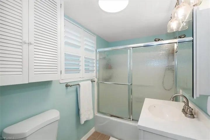 Bathroom featuring combined bath / shower with glass door and vanity