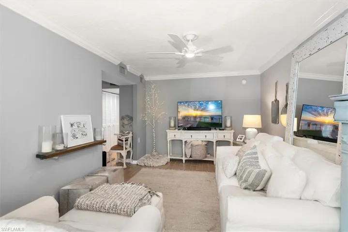 Cosy Living area with crown molding, wood finished floors, and ceiling fan