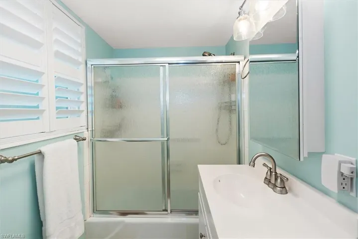 Full bathroom with combined bath / shower with glass door and vanity