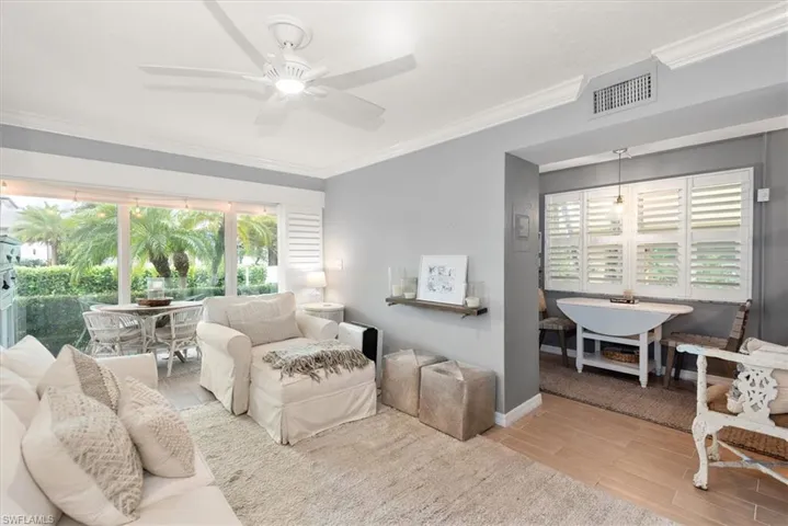 Living area with crown molding, wood finished floors, plenty of natural light, and ceiling fan