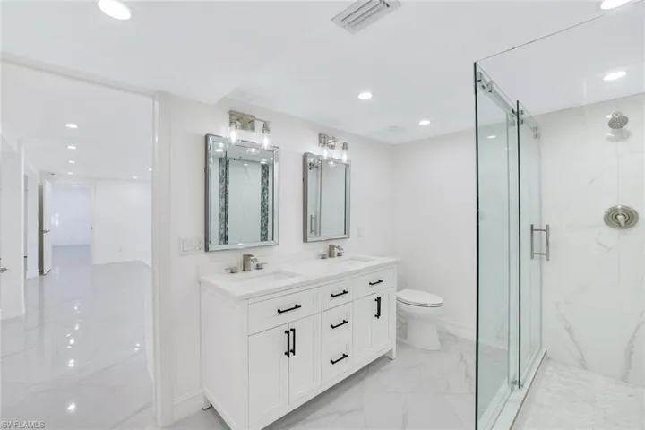 1st floor Bathroom featuring  a double vanity, toilet, and a frameless shower