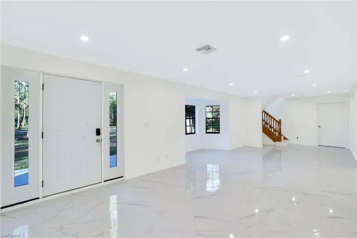Front door entrance leading to living room with dining area and a full kitchen
