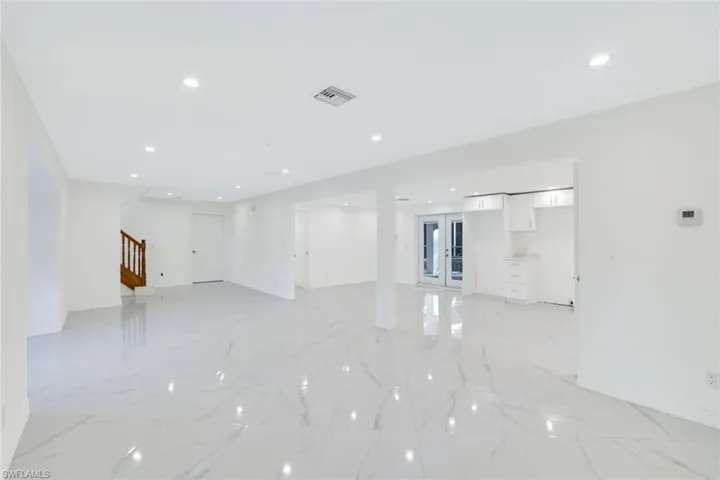 Front door entrance area leading to living room with dining area and a full kitchen and french door leading to the pool