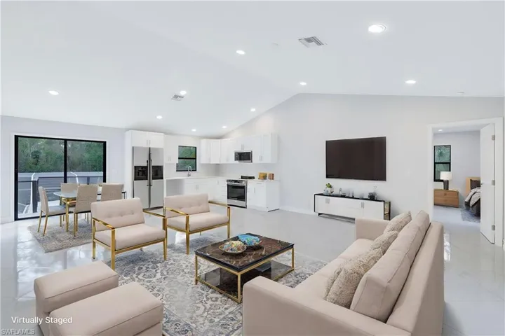 Staged 2nd floor living room with a full kitchen, high vaulted ceiling and sliding doors that lead to balcony overlooking the pool