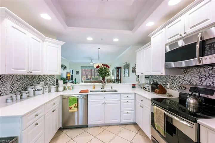 Kitchen with sink, kitchen peninsula, appliances with stainless steel finishes, and a raised ceiling