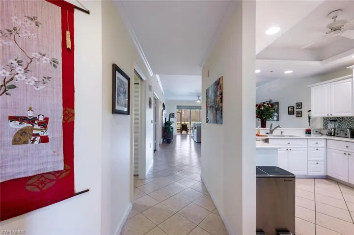Hall with sink, ornamental molding, light tile patterned floors, and a tray ceiling