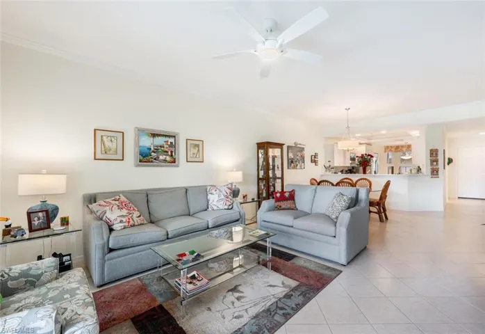 Living room featuring ornamental molding, light tile patterned flooring, and ceiling fan